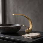 Curva brass curved basin faucet — styled on a stone vanity