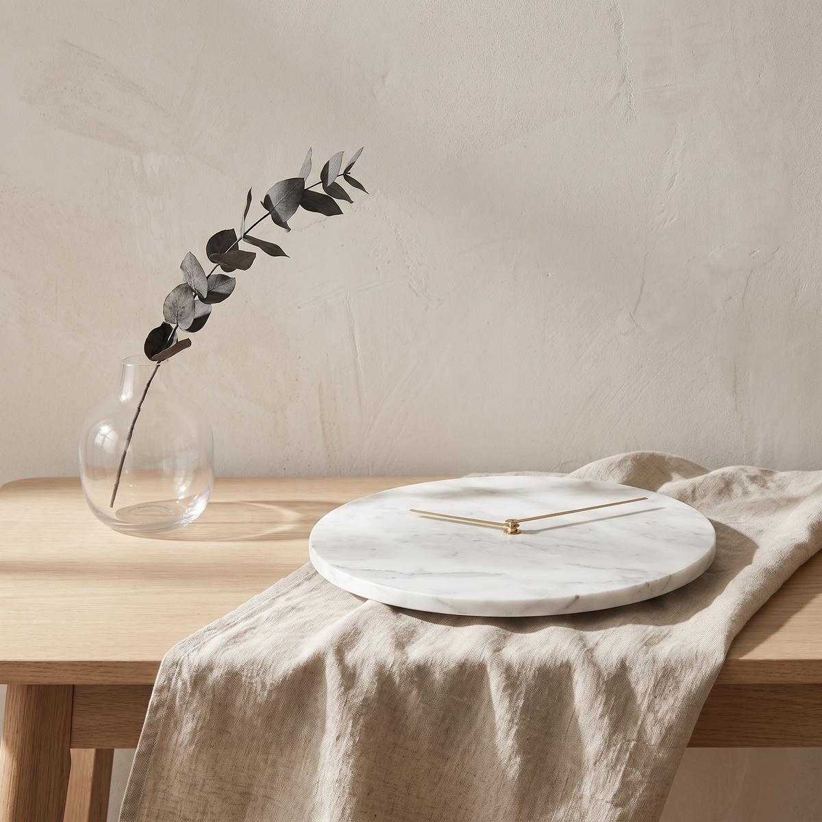 Veined marble and brushed brass detail on a pale wood console with linen runner