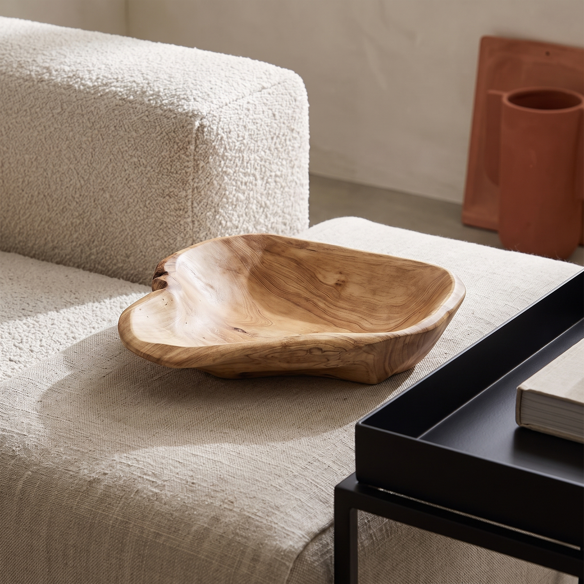 Layered natural materials, carved wood bowl on oatmeal linen beside boucle upholstery